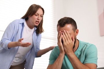 Fototapeta premium Betrayal. Angry woman shouting at her frustrated husband at home, selective focus