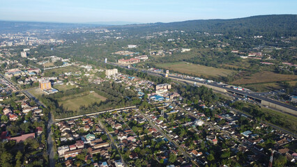Scenic aerial view of a vibrant city sprawling towards lush green hills and mountain range