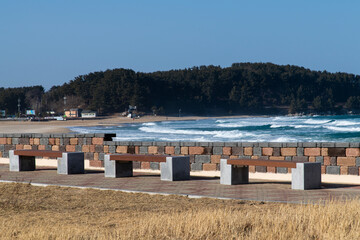 idyllic seascape with empty benches and breaking wave in winter