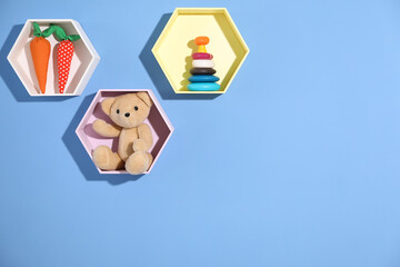 Obraz premium Honeycomb shaped shelves with different toys on blue background. Space for text