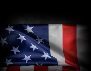 American flag partially folded in dramatic lighting against a dark background
