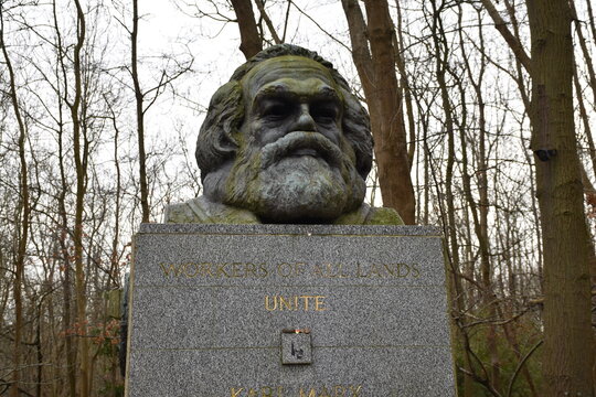 Sculpture of Karl Marx at Highgate Cemetery, London, symbolizing historical discussions on socialism and workers' rights amidst serene natural surroundings.