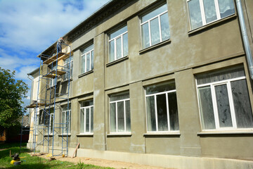 A builder prepares the surface of an old building facade in preparation for applying plaster during renovation.