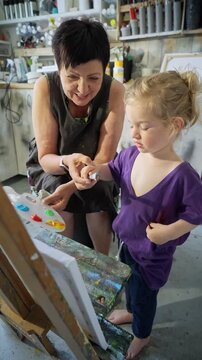 Child painting with an grandmother in a cozy art studio. Candid indoor moment of creativity and learning. Artistic lifestyle scene with real people and natural light.