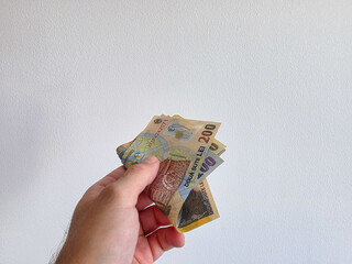 Romanian lei bank notes held in hand against a white background