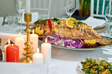 A beautifully presented dish of whole fish garnished with herbs, lemon, and colorful vegetables, elegantly arranged for a special dining experience.