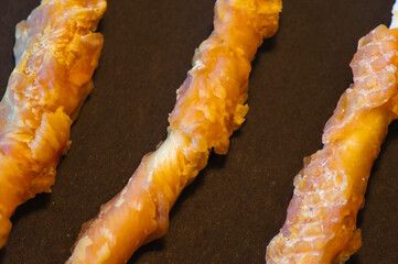 Close-up of Three Twisted Dog Treats on a Dark Background - Pet Food Snack