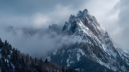 Misty Snow Covered Mountain Peak with Dramatic Cloudscape and Forested Slopes
