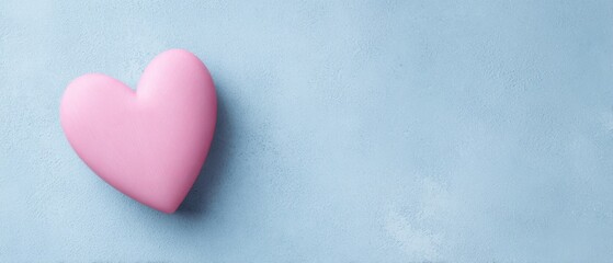Obraz premium The pink heart symbolizing love on a soft blue background for romantic themes