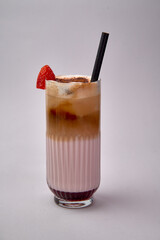 A Refreshing Layered Smoothie Drink with Creamy Milk, Strawberry Garnish, and a Decorative Straw...
