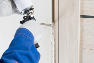 the process of installing a door frame and sealing the mounting foam with a gun