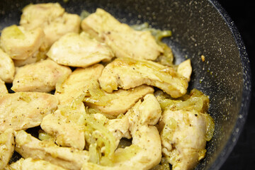 Sauteed chicken pieces with caramelized onions in a frying pan, showcasing a delicious meal preparation process and highlighting the textures and colors of the ingredients