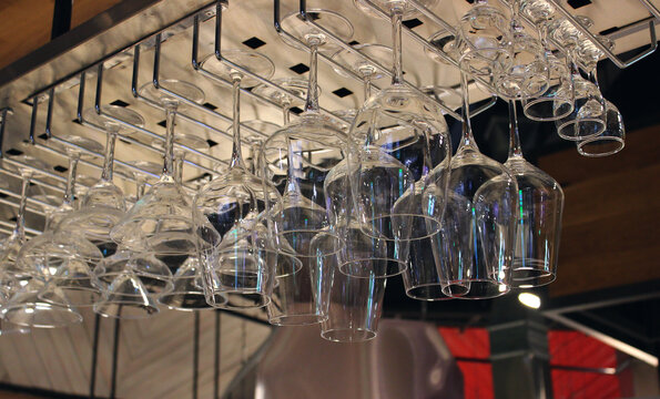 Vodka shot glasses, wine glasses and cocktail flutes hang upside down over the bar desk
