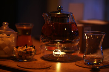 Cozy Evening Tea Setup with Warm Lighting, Snacks, and Steaming Teapot