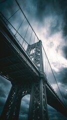 Dramatic upward view of a tall bridge against a cloudy, moody sky