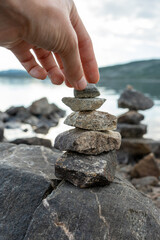 A woman hand building a cairns by the lake in Norway