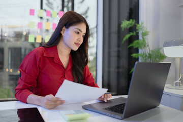 business woman working on laptop with paper document at office.