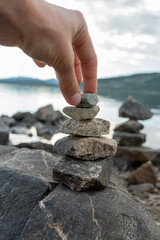 A woman hand building a cairns by the lake in Norway
