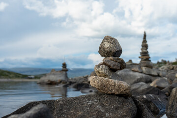 Stone cairns in the wind in Norway near a lake.