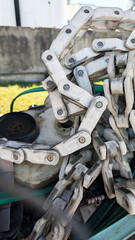 Close-up view of a heavy-duty metal chain resting on machinery, showcasing intricate links, with green machinery components in the background, emphasizing industrial strength and durability