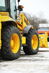 Obraz premium Yellow Construction Loader with Snow-Covered Ground and Trees in Background