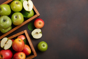 Ripe red and green apples in wooden box on a rusty background