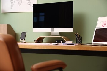 Stylish workplace with modern computer, other devices and stationery on wooden desk indoors