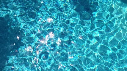 Shiny water. Ripples in the pool reflecting the sun. Sunlight reflects off the vibrant turquoise pool water. Deep blue pool water.