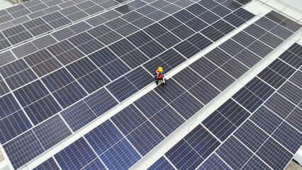 Worker performs maintenance on solar panels at rooftop installation in bright daylight