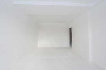 bright, empty room with white walls, ceiling, and floor. A doorway is visible to the right