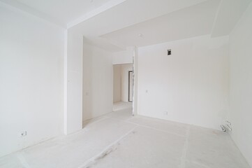 bright, unfinished room with white walls, ceiling, and floor. Open doorways lead to other spaces in the building