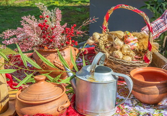 Still life with a kettle, ceramic pots and a basket of garlic