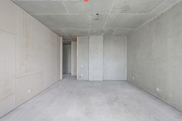 unfinished room with bare concrete walls, floor, and ceiling. The space is empty and shows electrical wiring