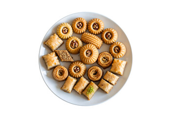 Middle Eastern mamoul cookies and assorted baklawa. Seen from above. Arabic baked treats with nuts on a white plate on a dark wooden table. Cookies for the Ayd El Fithr celebration.

