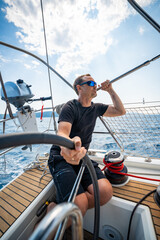 Obraz premium Man at the helm of a sailing yacht near Croatia, steering the boat through open water. Leadership, control, sailing lifestyle and freedom at sea.