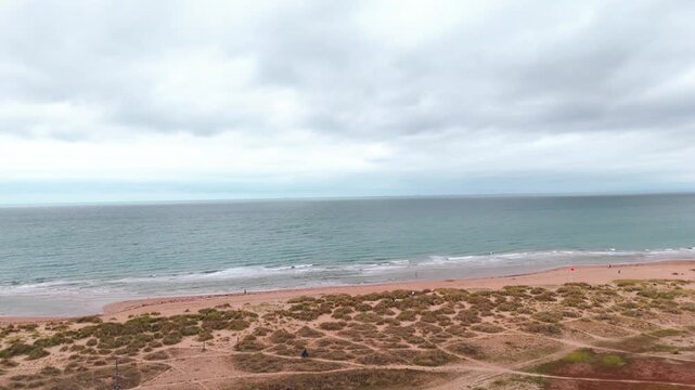 Aerial drift over tranquil coastal landscape with rolling waves and sandy shores