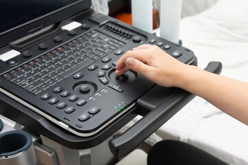 Medical professional operating diagnostic ultrasound equipment. Image shows detailed keyboard and control panel in clinical environment.