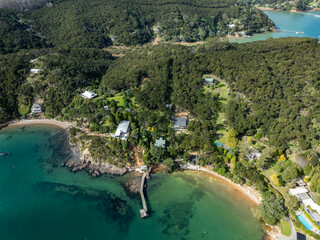 Aerial view of coastal homes nestled amongst lush green forest and clear turquoise waters in New...
