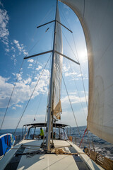 Fototapeta premium White sails filled with wind, seen from the bow of a sailing yacht near Croatia. Freedom, clean energy, adventure and mindful travel on the open sea.
