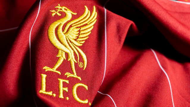 Close-up of Liverbird emblem on red Liverpool home kit with New Balance branding, focusing on detailed stitching and iconic club symbol