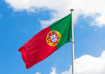 Traditional Portuguese national flag waiving in wind outside in park with blue sky in background