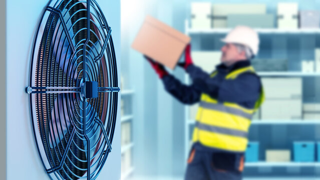 Man with box in freezer. Warehouse refrigerator at enterprise. Air conditioner for cooling air inside refrigerator. Blurred worker inside freezer. Warehouse for storing frozen products