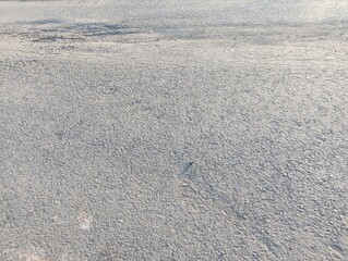 The image shows a severely cracked and damaged asphalt road. The surface is uneven with multiple long, deep cracks running down the middle.
