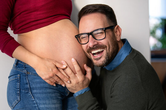 Beautiful pregnant woman and her handsome husband are smiling while spending time together