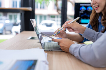 Two people are looking at a laptop with a pen in their hands