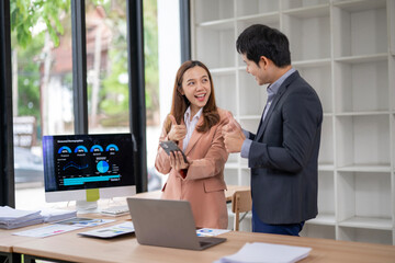 A man and a woman are standing in front of a computer monitor