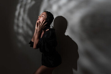 Fashion Portrait of Elegant Woman in Black Balaklava with Dramatic Shadows on Background