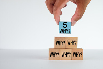 Hand completing the 5 Whys pyramid on wooden blocks. A concept for the 5 Whys problem-solving technique, root cause analysis (RCA), lean management, and continuous improvement (Kaizen).