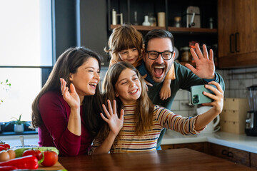 Happy parents with children using smartphone together at home. Family watching video having fun