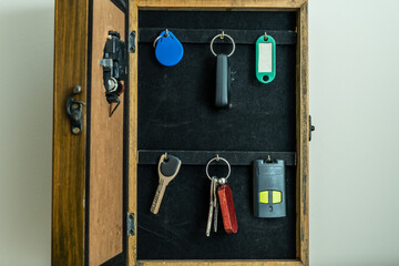 Home key cabinet with keys and buzzers hanging. Key rack in a box with a door on the wall